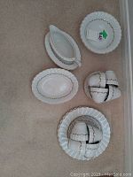 Full view of arranged stoneware set including plates, cups, saucers, gravy boat with tray, and serving bowls on carpeted floor