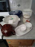 Photo showing Corelle lidded baking dishes, ramekins, canisters, and Brown Betty teapot on a countertop.