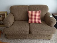 Front view of the love seat showing brown chenille upholstery and red checkered pillow on right cushion.
