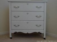 Full frontal view of the vintage painted dresser showing three drawers with brass-accented handles and caster wheels.