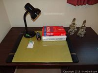 Full view of lot on desk showing molded glass horse bookends, two hardcover books, black goose-neck desk lamp, carved wooden duck, and ink blotter.