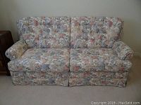 Front view of double size sofa bed in floral patterned upholstery showing two back cushions and two seat cushions with minor fabric fading.