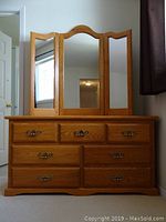 Front view of oak dresser with 7 drawers and attached three-way mirror