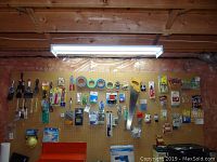 Wide view of pegboard wall with various handyman supplies including saws, tapes, brushes, and tools hung neatly.