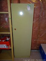 Front view of closed metal pantry cabinet, showing intact original paint and latch handle.