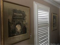 Close up photo showing one of two framed pen and ink prints on beige wall near window, showing detailed architectural drawing of Rome 1819