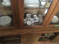 Photo of china set inside display cabinet showing plates and cups arranged.