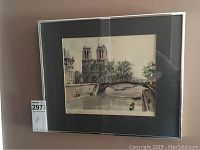 Framed signed watercolour painting showing Paris Notre Dame and the Seine river, with black matting and silver frame, photo taken from a slight angle.