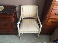 Front view of wooden armchair with upholstered striped fabric seat and backrest.