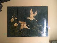 Four panel artwork with flowers and two flying birds on a dark green background, showing entire set laid flat against wall.