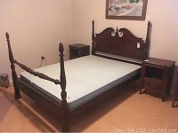 Full view of the queen size 4 poster bed made of dark wood, showing the mattress inside the frame and tapered posts at each corner.