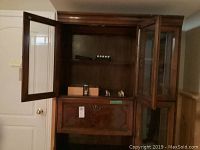 Front view of wood china cabinet with open glass door showing glass shelves and empty interior.