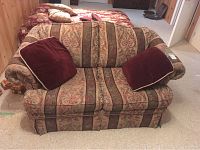Front view of the two-seater loveseat with patterned floral and striped fabric upholstery, showing two burgundy throw pillows on either side.