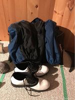 Brooks XL jacket laid out showing front with black body and blue sleeves on wooden background with shoes on carpet