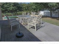 Patio table with six matching metal arm chairs on wooden deck outdoors, also includes umbrella stands visible near table.