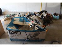 Ryobi miter saw on top of its original blue box with specs visible, showing the saw mounted on sliding rails with electric cord attached.