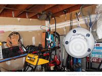 Gas powered string edgers along with various other tools and equipment stored in garage showing storage environment and context.