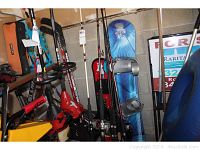 Photo showing snowboards, fishing rods, golf cart, and other sports equipment clustered in corner against concrete block wall