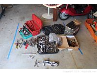 Overview photo showing an assortment of sockets, wrenches, hand tools, and toolboxes arranged on a garage floor.