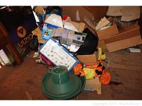 Photo shows the green plastic Christmas tree stand with multiple cardboard boxes around it containing various holiday items, including some orange and black fabric likely part of the Jack O Lantern inflatable.