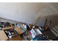 Wide view of the garage floor showing various tools, boxes, and equipment scattered including a hydraulic floor jack and hand tools.
