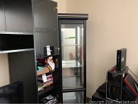 Side view of black curio cabinet with framed glass door and visible interior shelves