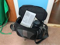 Olympus E-500 camera body and lenses inside a black camera bag, manual booklet visible.