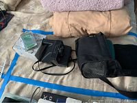 Photo showing vintage Polaroid Land camera, white instant film box, and accessories placed on bed.