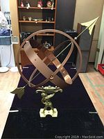 Front view of the whole sundial showing the metal rings, arrow gnomon, and target room shutter background.