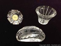 Three vintage Swedish crystal pieces on black background: Orrefors quartz clock, Orrefors small bowl, Jonasson rabbit paperweight