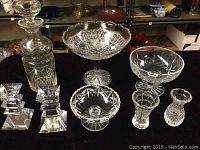 Photo of all crystal and glass items together showing decanter, candlesticks, bowls, vases, and cross