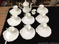 Overhead view of entire tea set laid out on black surface showing all cups, underplates, teapot and creamer.