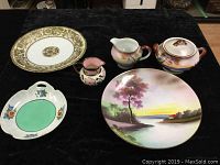 Full set of dinnerware and decorative plates on black cloth background.