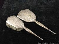 Photo of silver backed hairbrush and clothes brush with etched decorative patterns.