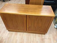 Front view of closed teak cabinet showing wood grain and flat top with some wear.