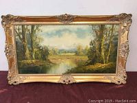 Full view of the framed oil painting showing the landscape scene with river and trees.