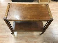 Top down view of the rectangular vintage wooden cart showing top shelf with visible water marks and side rails.