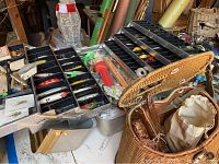 Opened metal tacklebox showing several compartments with multiple fishing lures including crankbaits and spoons in various colors.