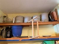 Three stacks of white porcelain plates with gray star border on wooden shelf
