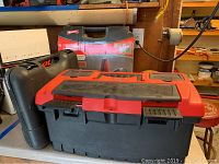Photo showing the Keter toolbox in closed state along with Arrow nail gun box and Black and Decker case.