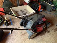 Side view of the Troy Bilt TB230 gas lawn mower showing the handle, wheels and attached grass catcher bag.