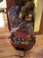 Photo showing three Vermont bears in plastic bags and a Harrods bear with the Noah's Ark wooden birdhouse decorated with multiple artist-signed wooden birds.