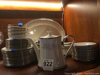 Full view of stacked plates, cups, and teapot showing the entire china set with Snow Lily pattern and silver trim