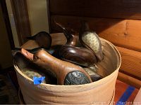 Photo showing several wooden bird decoys in round wooden container including a large loon and other smaller birds.