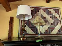 Both lamps shown on a dark wood surface in front of a quilted wall hanging.