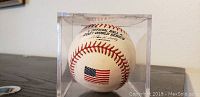 Front of the official 2001 World Series baseball with American flag and inscription, displayed in clear case.
