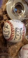 Signed New York Mets baseball showing multiple player signatures clearly visible, placed next to the clear display case base.