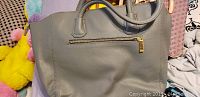Grey faux leather handbag showing front side with gold zipper pocket