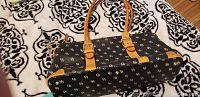 Side view of Dooney and Bourke handbag lying on patterned blanket showing shape and strap detail