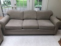 Front view of beige three seater sofa showing three seat cushions and three back cushions with rounded arms.